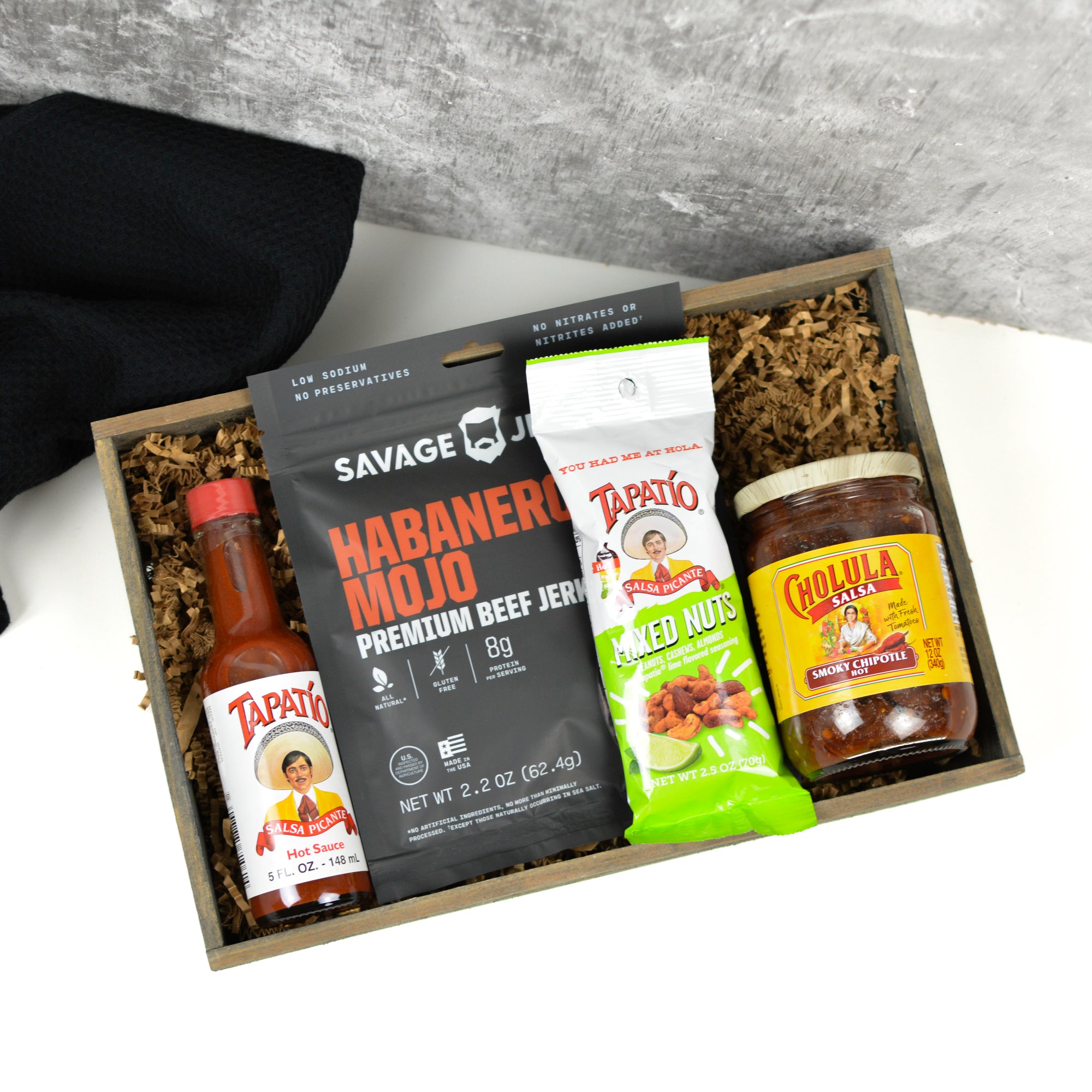 Gift box with spicy food products including Tapatio hot sauce, Cholula sauce, and Habanero Mojo jerky.